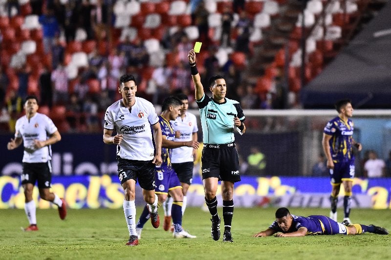 Daniel Quintero Huitrón, árbitro central, muestra tarjeta amarilla 