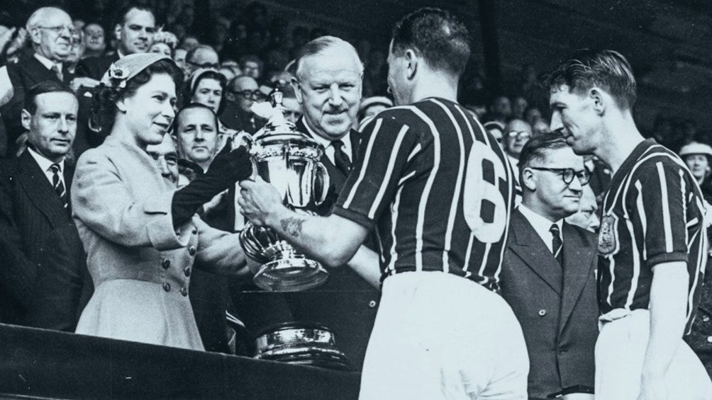 La Reina Isabel II entregando un trofeo al Man City