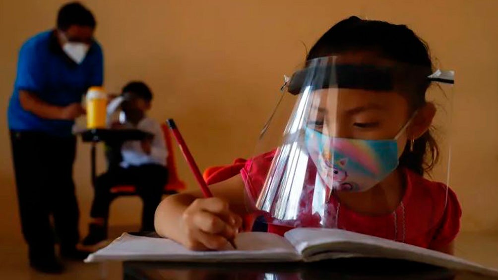 Niña escribe en su libreta durante una clase en tiempos de Covid-19