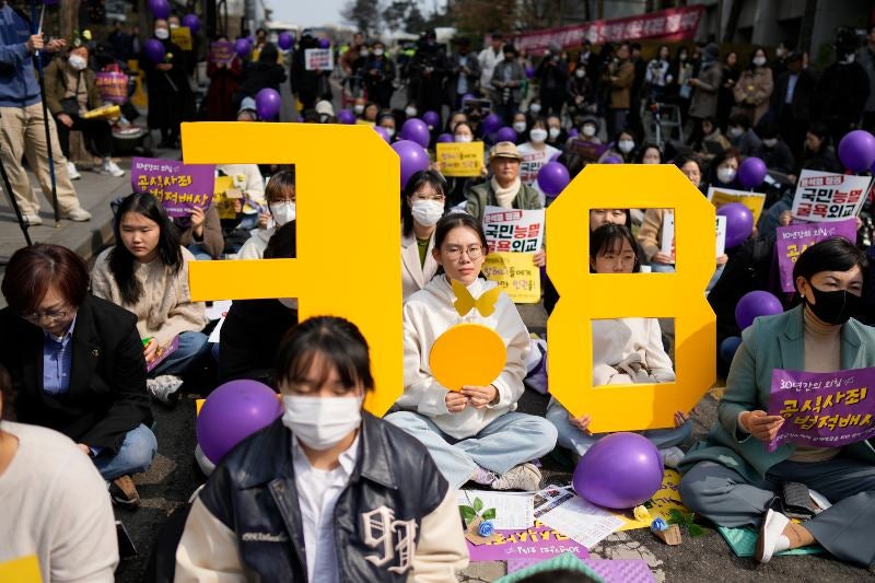 Participantes sostienen símbolos que representan el Día Internacional de la Mujer