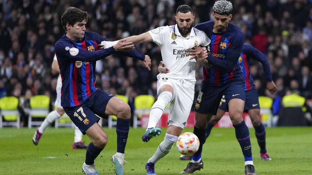 Benzema entre dos jugadores del Barcelona