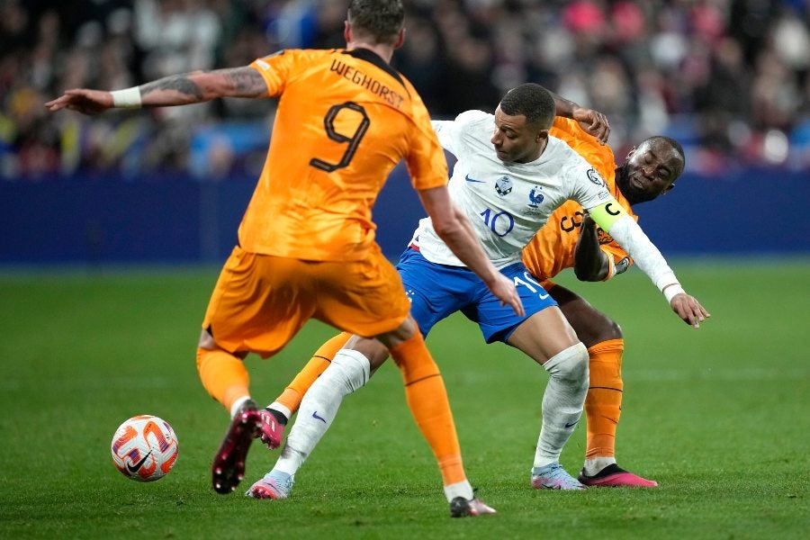 Mbappé luchando por el esférico entre dos jugadores 