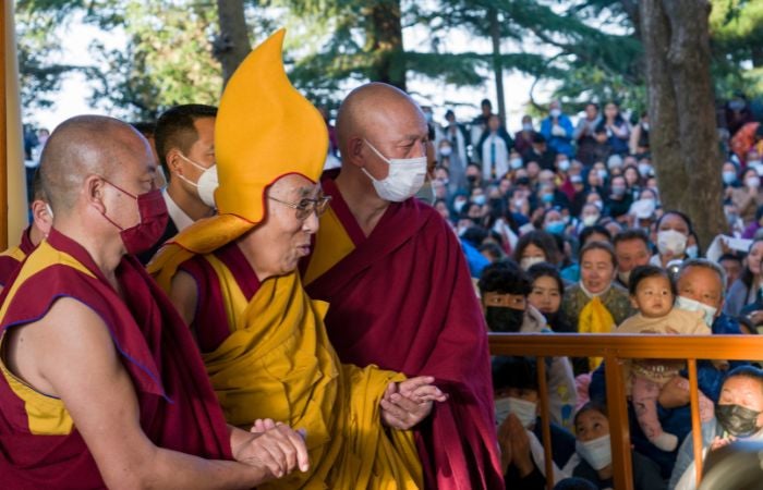 Dalai Lama siendo guidado por dos monjes budistas durante la pandemia 