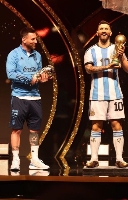 Messi viendo la estatua con su figura y la Copa del Mundo FIFA