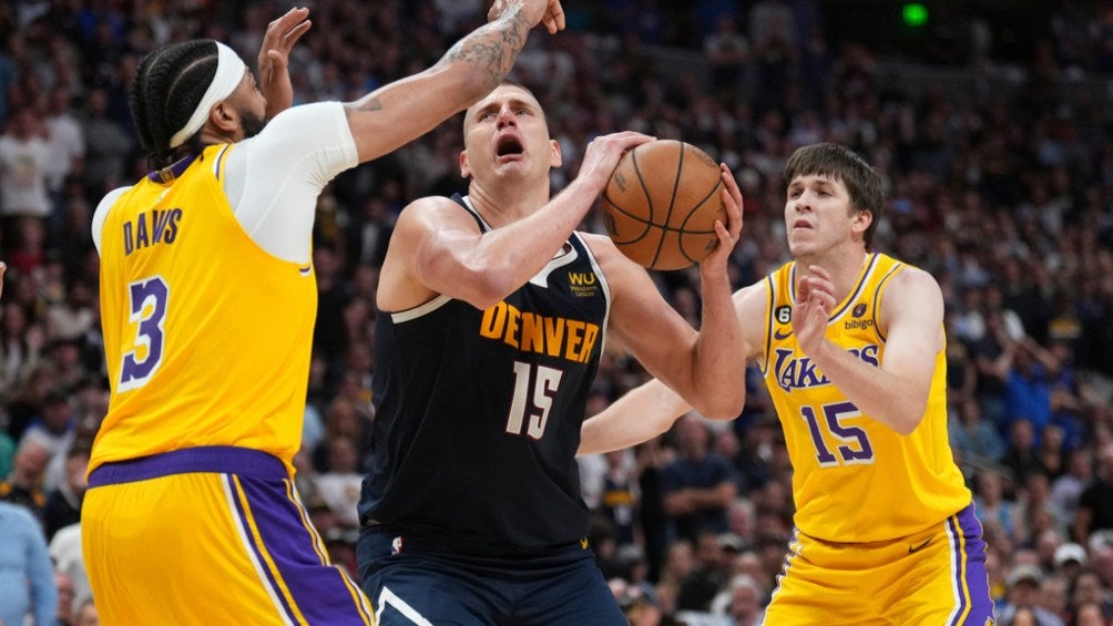 Nicola Jokic busca el canasto entre dos de los Lakers