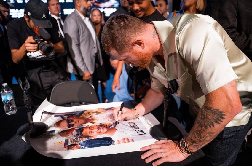 Saúl firmando una playera 