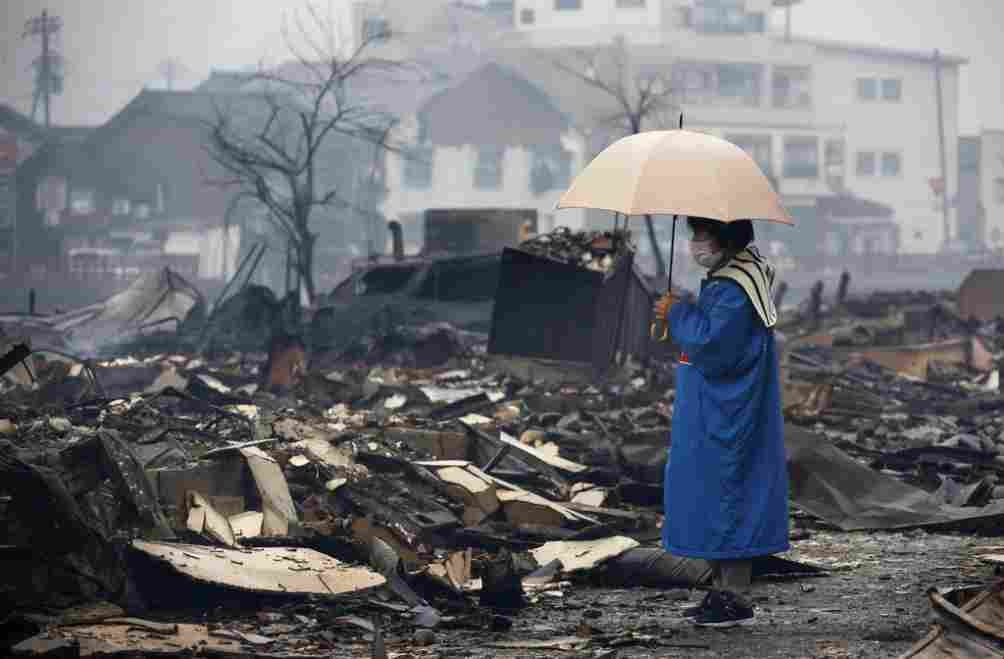 Una mujer de pie ante las ruinas provocadas por el terremoto