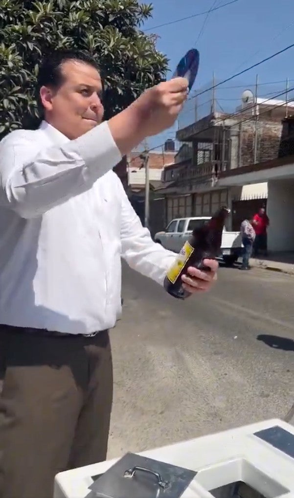 El político sorprendió por su manera de abrir las botellas con un CD.