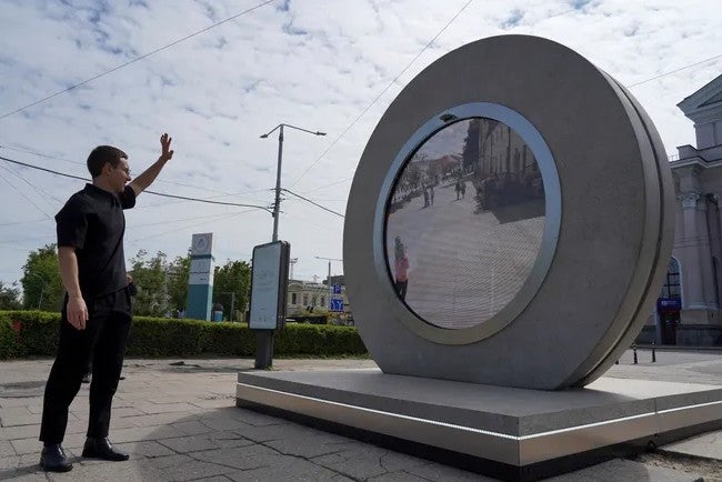 El artista lituano Benediktas saludando a través del portal en Lituana, en 2021.