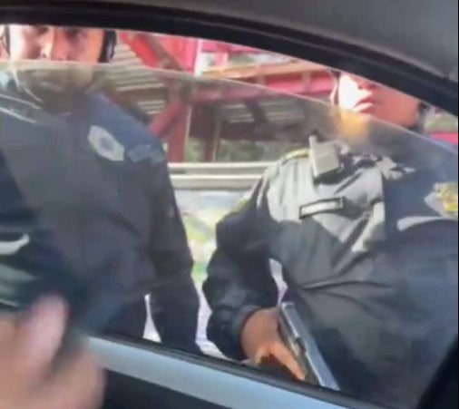 Un policía muestra su arma en forma de reto al conductor.