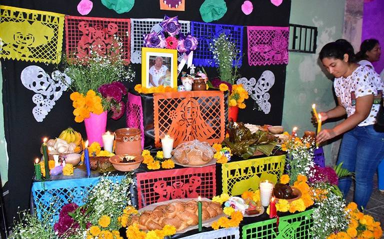 Las personas colocan ofrendas y fotografías en el altar recordando a sus seres queridos