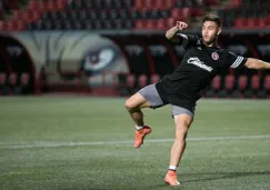 Héctor Villalba intenta patear un balón con la playera de Xolos