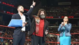 Finn Bálor (izq) entrega su título a Mick Foley (centro)