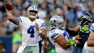 El QB de los Vaqueros de Dallas Dan Prescott intenta lanzar un pase