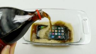 Un iPhone 7 en un refractario con refresco de cola