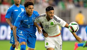 Henry Figueroa pelea un balón frente a Carlos Vela