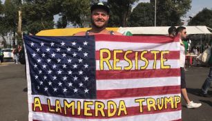 Estadounidense muestra una bandera de su país en la explanada del Azteca