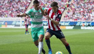 Osvaldo Martínez y Carlos Fierro disputan un balón en un partido entre Chivas y Santos