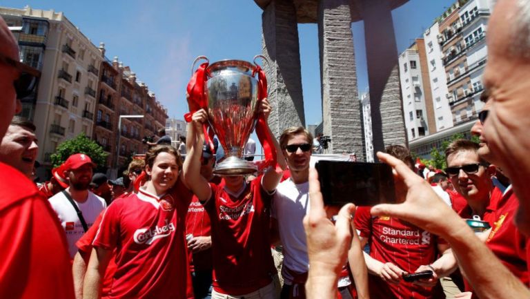 Aficionados del Liverpool posan con una Orejona