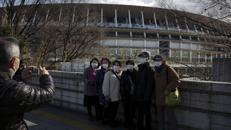 Aficionados japoneses se toman una foto con el Estadio Olímpico de Tokio de fondo